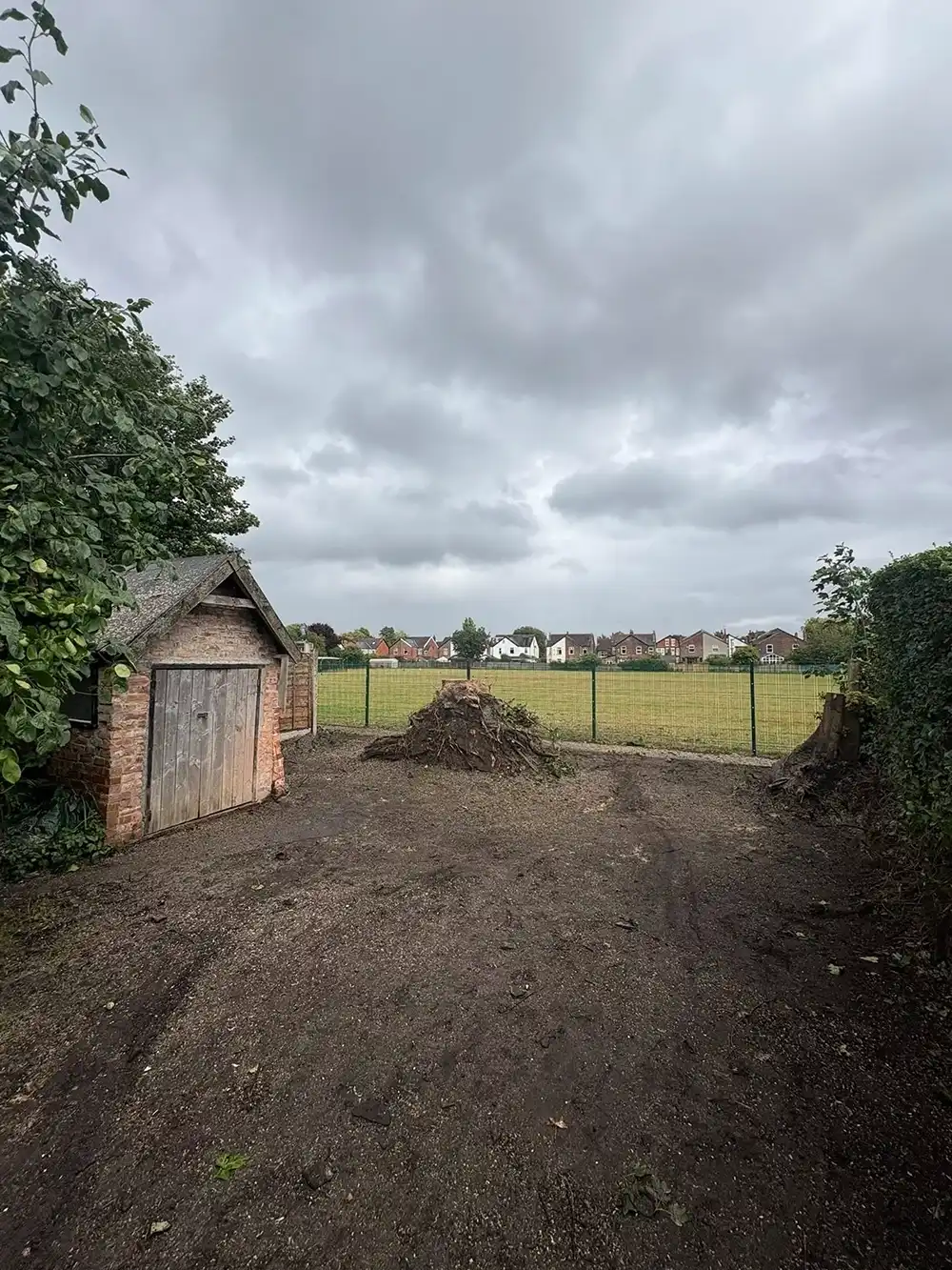 A dirt driveway with a shed and a fence.